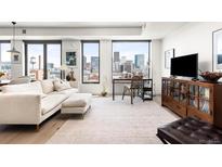 Bright living room features large windows with city views, hardwood floors, and comfortable seating arrangement at 1750 Wewatta St # 1230, Denver, CO 80202