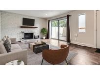 Bright living room features a white brick fireplace, hardwood floors, and sliding door access to outdoor space at 9605 E Kansas Cir # 53, Denver, CO 80247