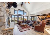 Bright living room features vaulted ceiling, large windows with mountain views, and stone fireplace at 1279 Estates Dr, Breckenridge, CO 80424