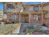 Charming home featuring a brick facade, covered entry, and well-maintained landscaping at 5214 S Ironton Way, Englewood, CO 80111