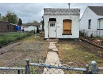 Small white brick home in need of repair, with a small yard and chain link fence at 1037 Hazel Ct, Denver, CO 80204