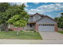 Two-story home featuring a lush front lawn, a covered porch, brick accents, and an attached two-car garage at 2253 E 100Th Pl, Thornton, CO 80229