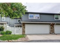 Two-story home with gray siding, stone accents and a white garage door and white fence at 2829 S Xanadu Way, Aurora, CO 80014