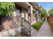 Charming front porch featuring brick accents, concrete steps, and a wooden railing at 239 W Jamison Ct, Littleton, CO 80120