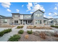 Inviting home with stone accents, a well-manicured lawn, and a charming covered front porch at 7484 W Atlantic Ln, Denver, CO 80227