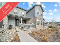 Charming two-story home featuring stone accents, a welcoming front porch, and professional landscaping at 7484 W Atlantic Ln, Denver, CO 80227