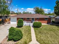 Charming brick home featuring a well-maintained front yard, walkway, and white picket porch at 7160 Canosa Ct, Westminster, CO 80030