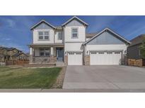 Charming two-story home features a three-car garage, covered porch, and manicured front lawn at 404 Dusk Ct, Erie, CO 80516