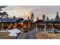 Stunning home exterior with a metal roof, stone accents and a circular driveway at sunset at 4446 Songbird Ln, Evergreen, CO 80439