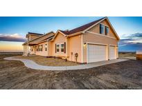 Charming two-story home boasts a three-car garage, neutral siding, and a neatly graveled yard at 4820 S County Road 137, Bennett, CO 80102