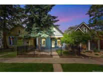 Charming blue home featuring a lovely front yard and a secure black fence at 269 Delaware St, Denver, CO 80223
