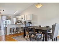 Open dining area with vaulted ceiling, modern light fixture, and access to the kitchen island at 12195 Grape St, Thornton, CO 80241
