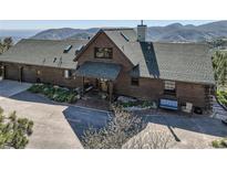 Charming log home with lush landscaping, covered porch, and mountain views at 10450 Hondah Dr, Littleton, CO 80127