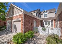 Charming exterior view of a two-story house with a brick facade, attached garage, and landscaped front yard at 9875 Greensview Cir, Lone Tree, CO 80124