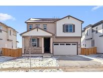 Charming two-story home featuring a covered porch and an attached two-car garage at 9165 Truckee Ct, Commerce City, CO 80022