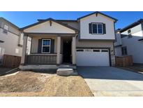 Two-story house with beige and brown siding, attached garage, and small front porch at 9165 Truckee Ct, Commerce City, CO 80022