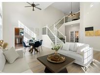 Bright, open living room with soaring ceilings, dining area, and modern staircase at 2089 Meadow Sweet Ln, Erie, CO 80516