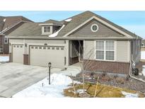 Charming gray home featuring an attached two-car garage and brick accents at 15842 Willow St, Brighton, CO 80602