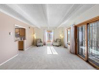 Bright living room features a beamed ceiling, large windows, and sliding door access to the outdoors at 2525 S Dayton Way # 1514, Denver, CO 80231