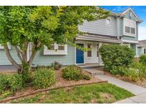 Charming townhouse featuring a well-maintained front yard with lush landscaping and a bright blue front door at 5895 Biscay St # D, Denver, CO 80249