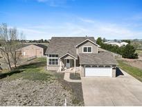 Charming two-story home with a spacious yard, complemented by an attached two-car garage and barn in the background at 16275 Electra St, Brighton, CO 80603