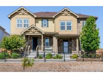 Charming tan townhouse with stone accents, well-kept landscaping and a cozy, covered front porch at 23293 E Jamison Dr, Aurora, CO 80016