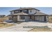 Modern glass garage doors and a wide driveway add curb appeal to this two story home's elevation at 9752 Canyon Wind Pt, Parker, CO 80138