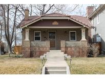 Charming brick home featuring a red tile roof, covered front porch, and manicured lawn at 1395 S Josephine St, Denver, CO 80210