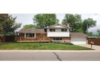 Charming two-story home with a brick facade, a large wooden porch, and a well-maintained lawn at 8120 S Jay Dr, Littleton, CO 80128