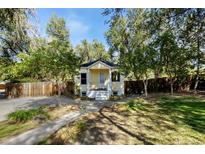 Charming single-story home with a walkway leading to the front door and mature trees in the front yard at 305 Jackson Ave, Firestone, CO 80520