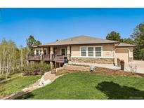 Charming ranch home with a stone facade, landscaped yard, and inviting deck, perfect for outdoor entertaining at 20413 Bald Mountain Ct, Monument, CO 80132