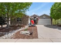 Charming brick home featuring a well-manicured yard, attached garage, and an inviting entrance at 12380 Jasper Pointe Way, Castle Pines, CO 80108