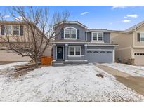 Charming two-story home with a covered front porch, shutters, and a two-car garage on a snow covered lot at 1963 Hogan Ct, Castle Rock, CO 80109