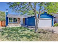 Charming blue home with stone accents, solar panels, well-kept lawn, and attached two-car garage at 3854 S Olathe Cir, Aurora, CO 80013