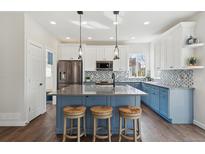 Bright, modern kitchen featuring a large island, stainless steel appliances, and stylish blue and white cabinetry at 1534 Stanley Dr, Erie, CO 80516