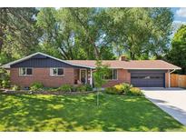 Charming single-story brick home boasts a well-manicured lawn and mature trees, offering great curb appeal at 13140 W 15Th Dr, Golden, CO 80401