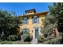 Charming yellow two-story home featuring classic architectural details, shuttered windows, and lush landscaping at 263 N Logan St, Denver, CO 80203