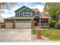 Charming two-story home featuring a well-manicured lawn, front porch, and three-car garage at 1535 Peach Ct, Brighton, CO 80601