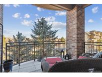 Relax on this balcony with brick pillar and beautiful mountain views with stylish patio seating and a black metal railing at 7865 Vallagio Ln # 207, Englewood, CO 80112