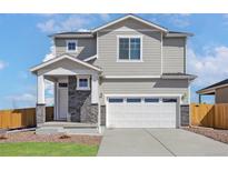 Charming two-story home with gray siding, stone accents, and a two-car garage in a Gathering-friendly neighborhood at 9454 Yampa St, Commerce City, CO 80022