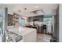 Stylish kitchen boasts an island with seating, gray cabinets, quartz countertops, and modern stainless steel appliances at 6311 Xavier St, Arvada, CO 80003