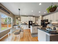Bright kitchen features white cabinetry, granite countertops, stainless steel appliances, and a dining area at 2861 Madison Ln, Broomfield, CO 80023