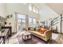 Bright living room with fireplace, large windows, and staircase at 8165 E Lowry Blvd # 310, Denver, CO 80230