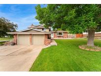 Charming two-story home with a brick facade, attached two-car garage, and a lush green lawn at 6798 Depew St, Arvada, CO 80003