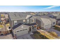 Beautiful two-story home with a well-maintained yard and covered front porch in a Gathering-friendly neighborhood at 753 Audubon Peak Dr, Erie, CO 80516