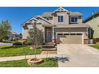 Two-story home with a beige exterior, well-kept lawn, and mature landscaping, creating a welcoming curb appeal at 10201 Rifle St, Commerce City, CO 80022