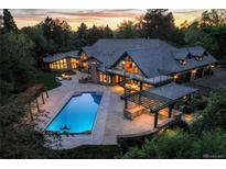 Stunning aerial view of a luxury home with a pool, outdoor kitchen, and patio at sunset at 1328 E Layton Ave, Cherry Hills Village, CO 80113