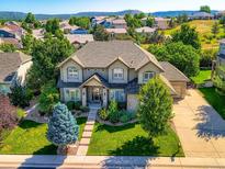 Beautiful two-story home featuring manicured lawn, lush landscaping, and an inviting facade, with mature trees at 3400 Elk Run Dr, Castle Rock, CO 80109