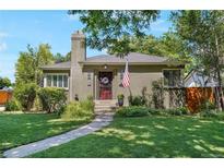 Charming home featuring a well-manicured lawn, stone walkway, and inviting front porch with an American flag at 675 Dahlia St, Denver, CO 80220
