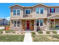 Charming townhouse with stone accents, a red door, and a cozy front porch with rocking chairs at 4316 S Netherland St, Aurora, CO 80015